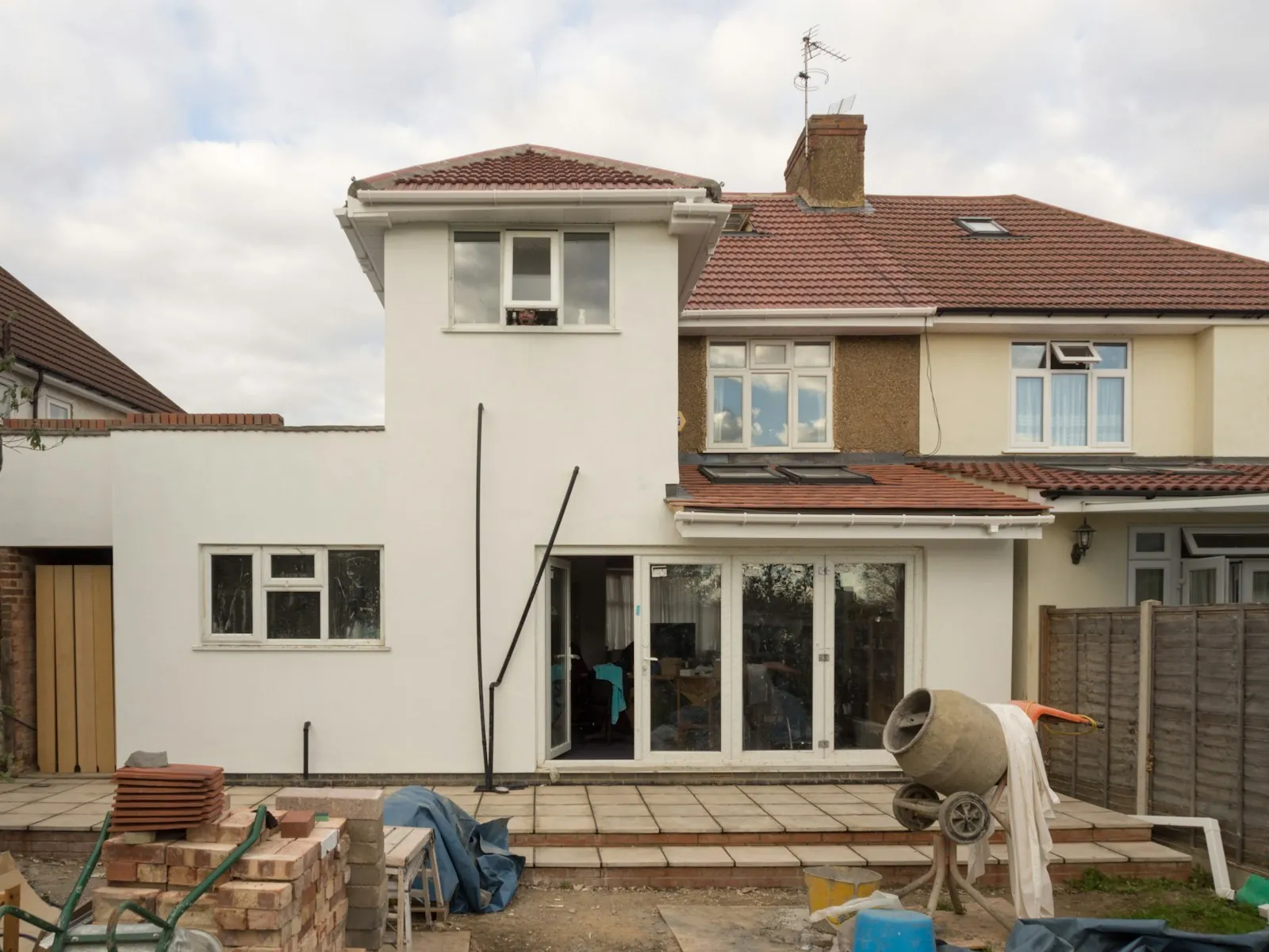 The same rear extension rendered in white with new windows and bifold doors, a cement mixer on the patio