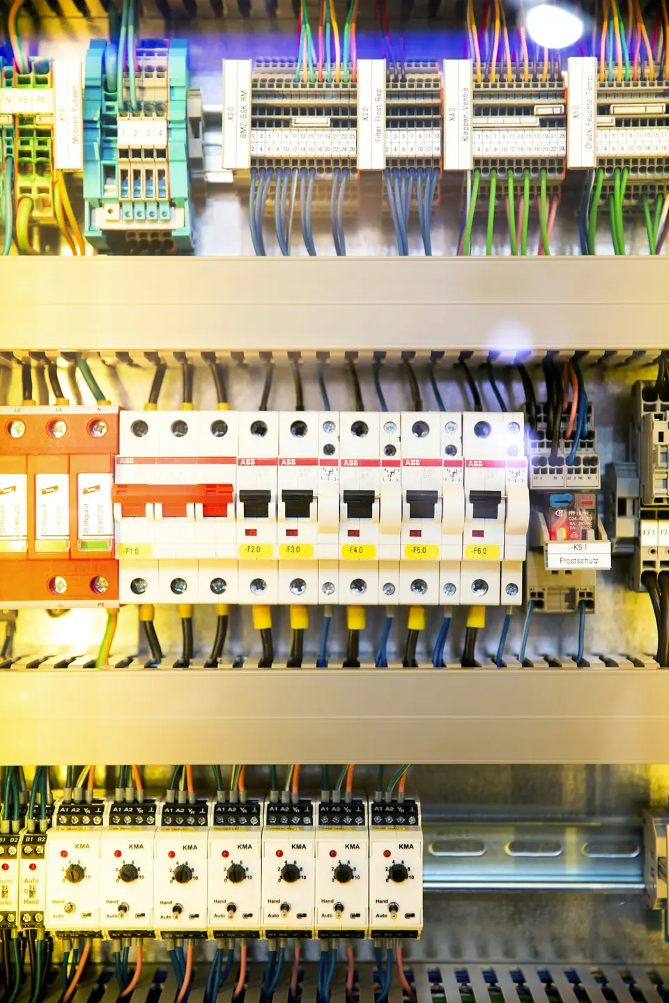 Rows of circuit breakers and neatly run coloured wiring in a distribution board